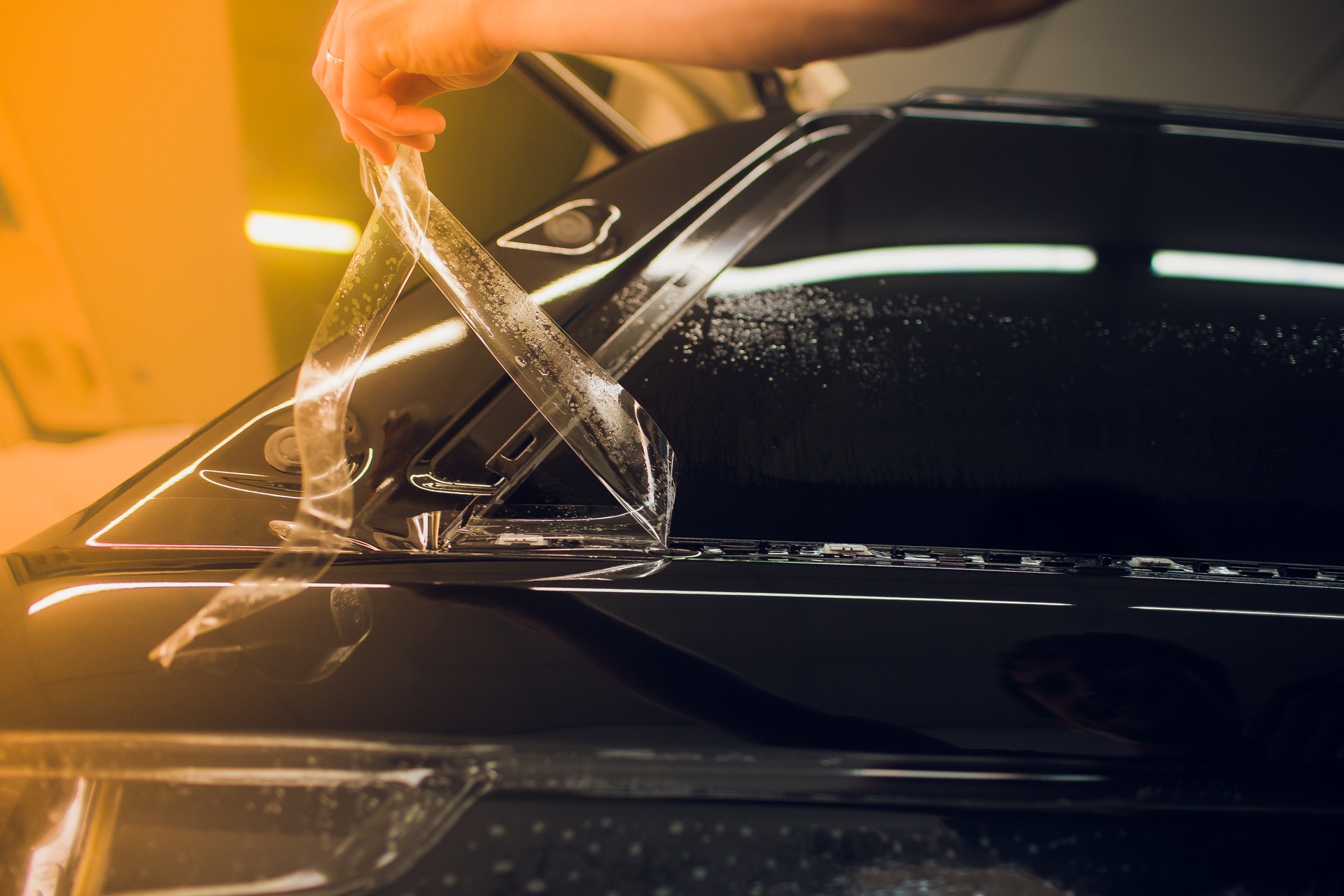 Worker hands installs car paint protection film wrap.